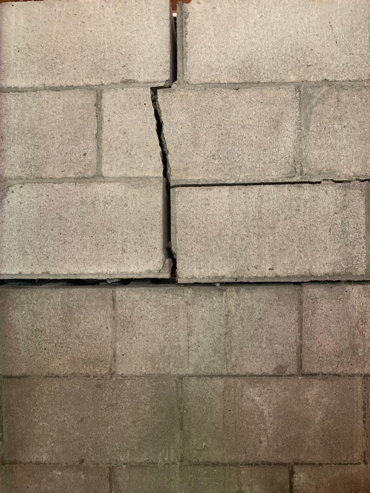 Bowing basement wall with a visible vertical crack near an exterior downspout