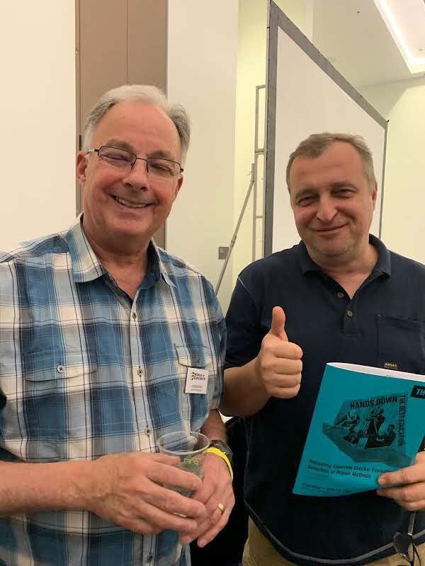 Raf at the World of Concrete trade conference, photographed with a senior industry instructor while holding the official Repairing Concrete Cracks training booklet.